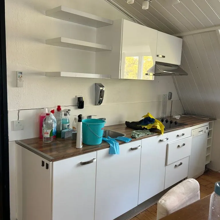 De bestaande keuken voor de demontage, met bovenkastjes en een werkblad langs de wand