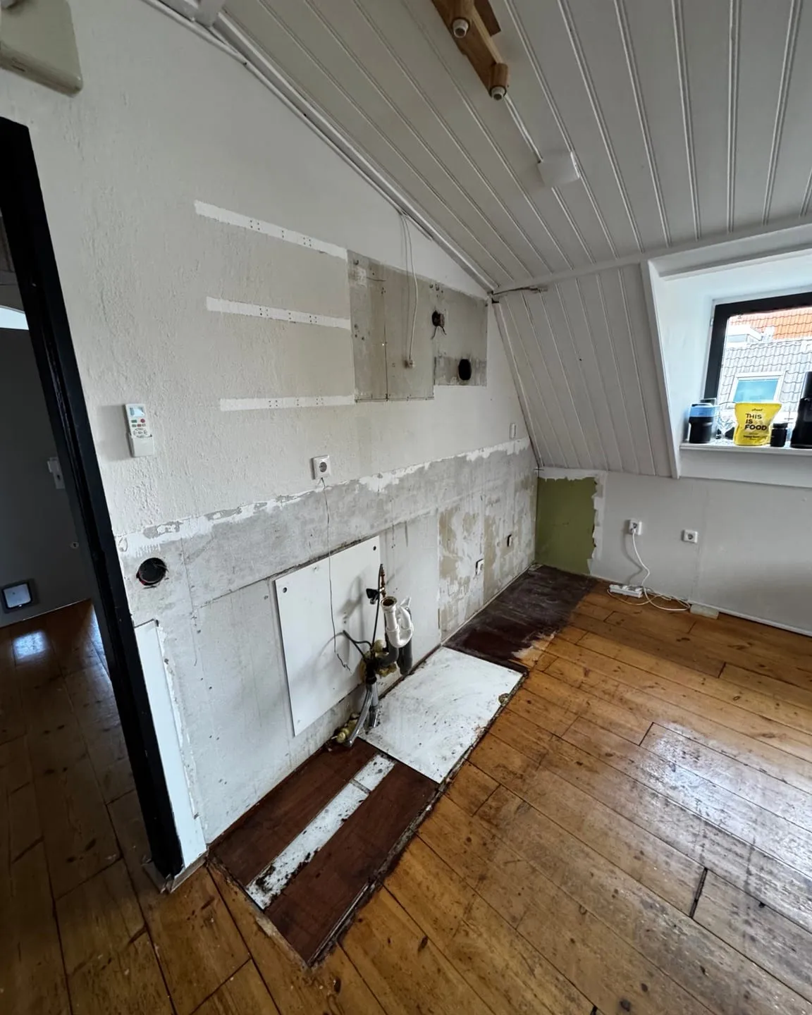 De keukenwand na de demontage, met de leidingen en aansluitingen vrij in het zicht