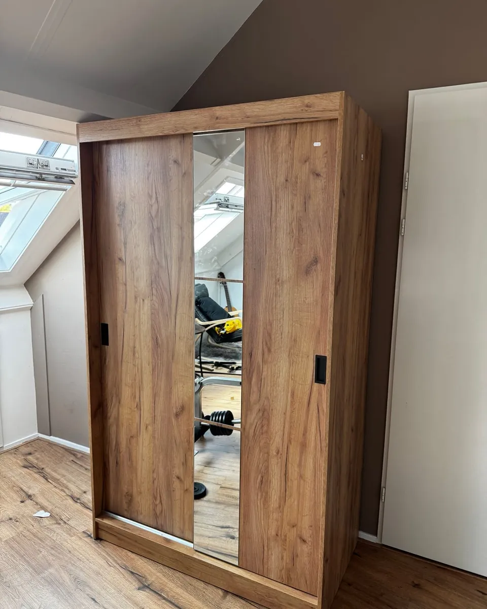 Afgemonteerde kledingkast in houtlook met een spiegeldeur en een houten schuifdeur