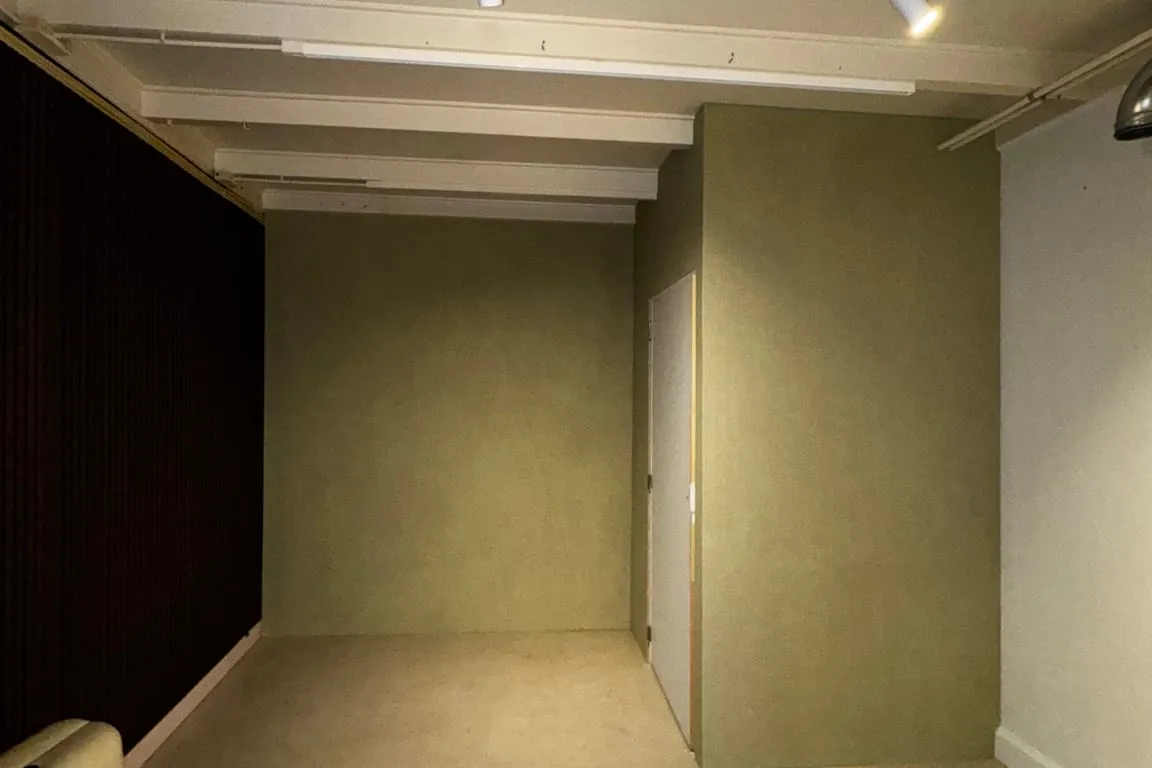 Opgeleverde kamer met zachtgroene wanden, witte plafondbalken en spots aan een rail