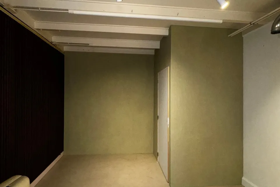 Opgeleverde kamer met zachtgroene wanden, witte plafondbalken en spots aan een rail