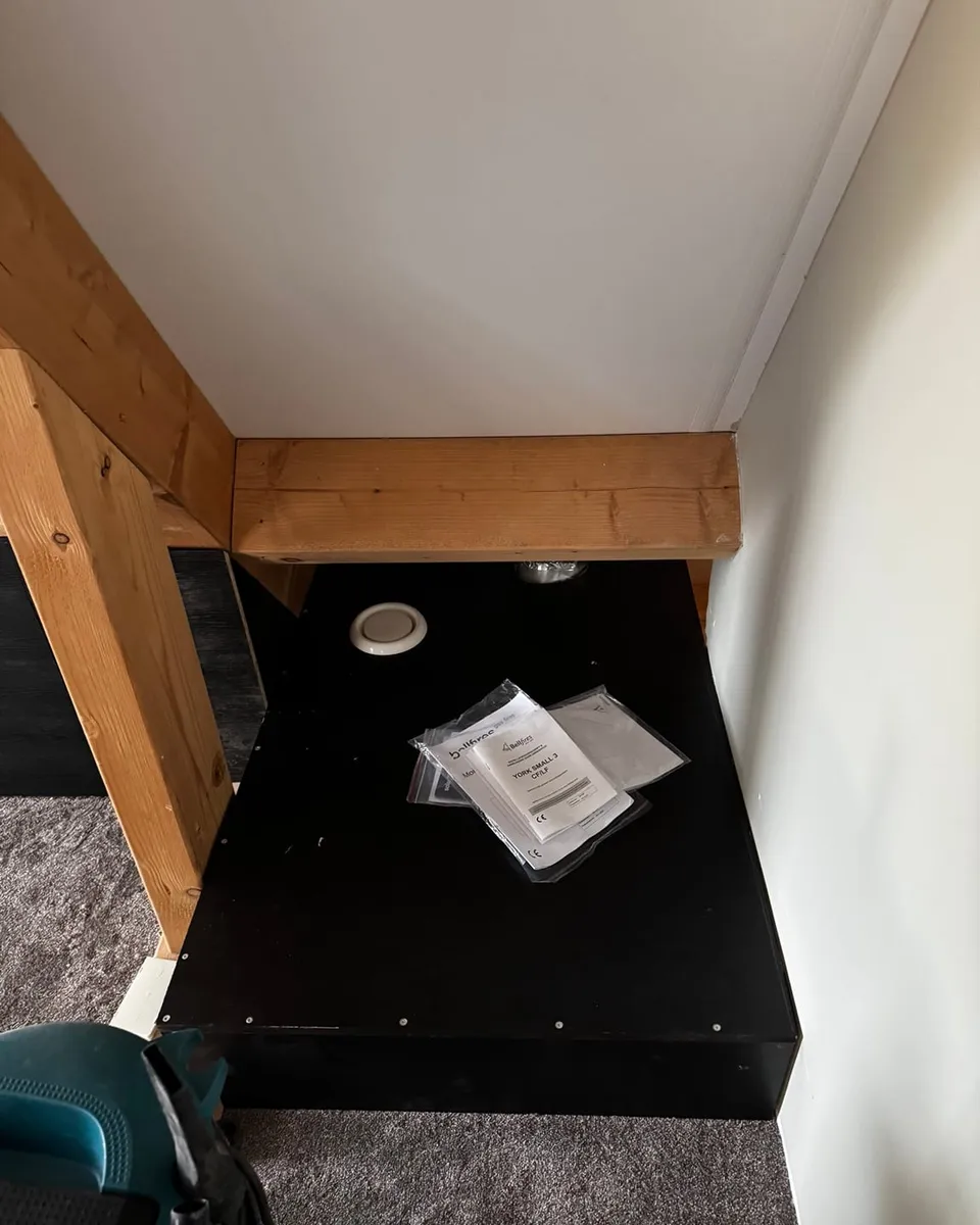 Zwart afgewerkt inbouwvlak in de hoek onder het schuine dak, naast een houten balk