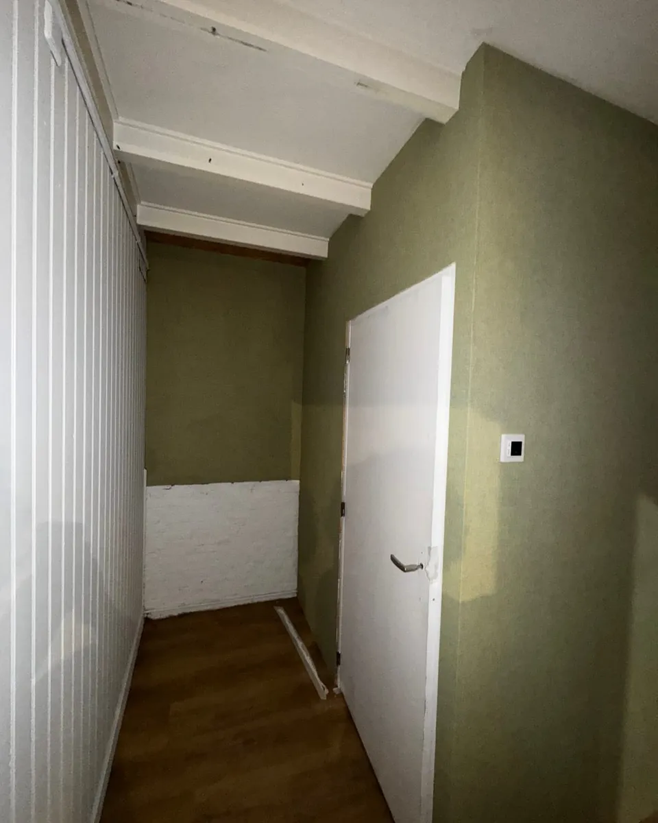Detail van de afwerking, waar de zachtgroene wand strak op het witte paneelwerk aansluit